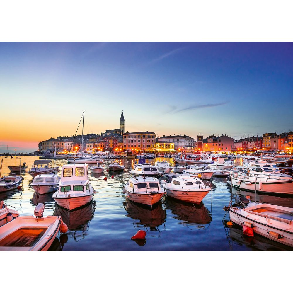 Porto pieno di barche al tramonto, con una città sullo sfondo.