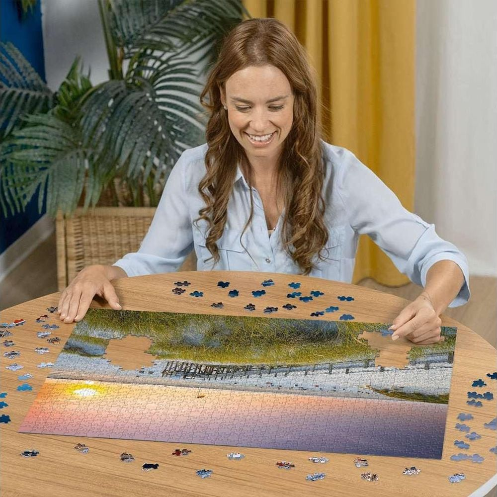 Frau vervollständigt ein Puzzle mit Strandmotiv bei Sonnenuntergang.
