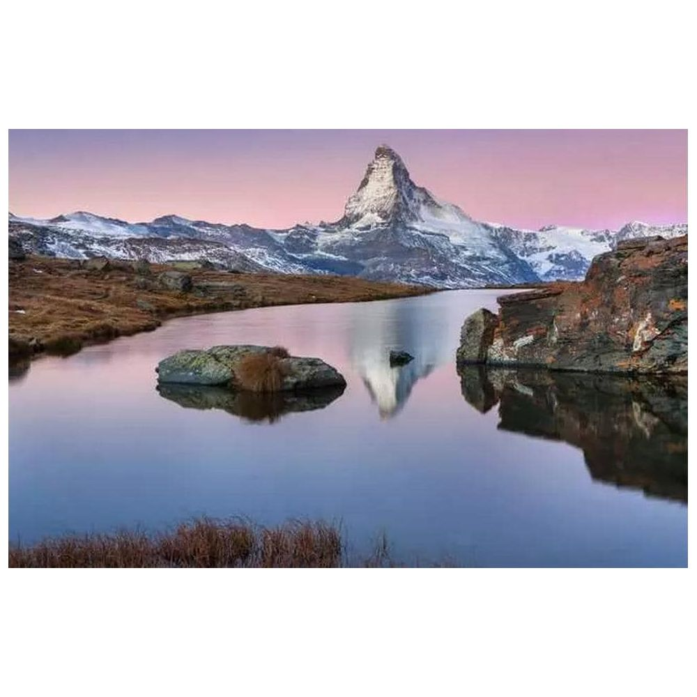 Une montagne enneigée se reflète dans un lac calme au lever du soleil.