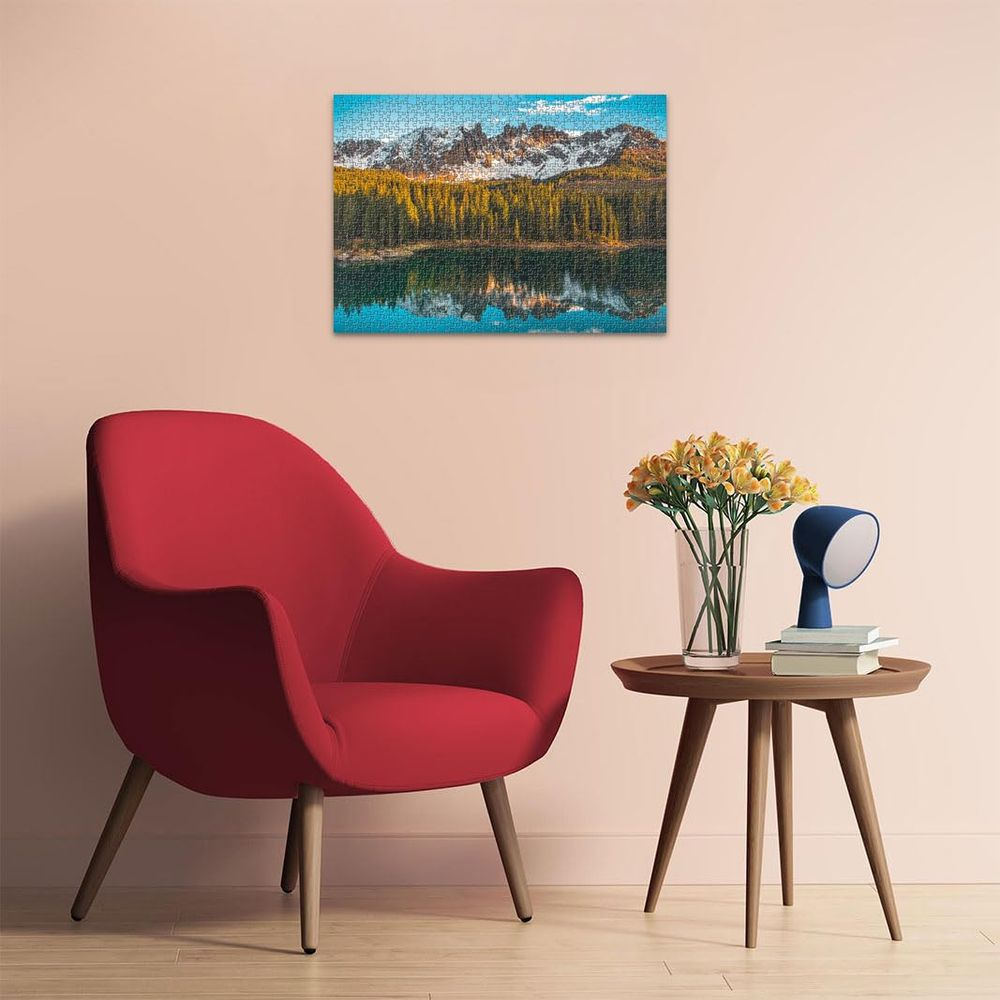 Un puzzle di montagne, alberi e lago riflesso in acqua calma è appeso a un muro.