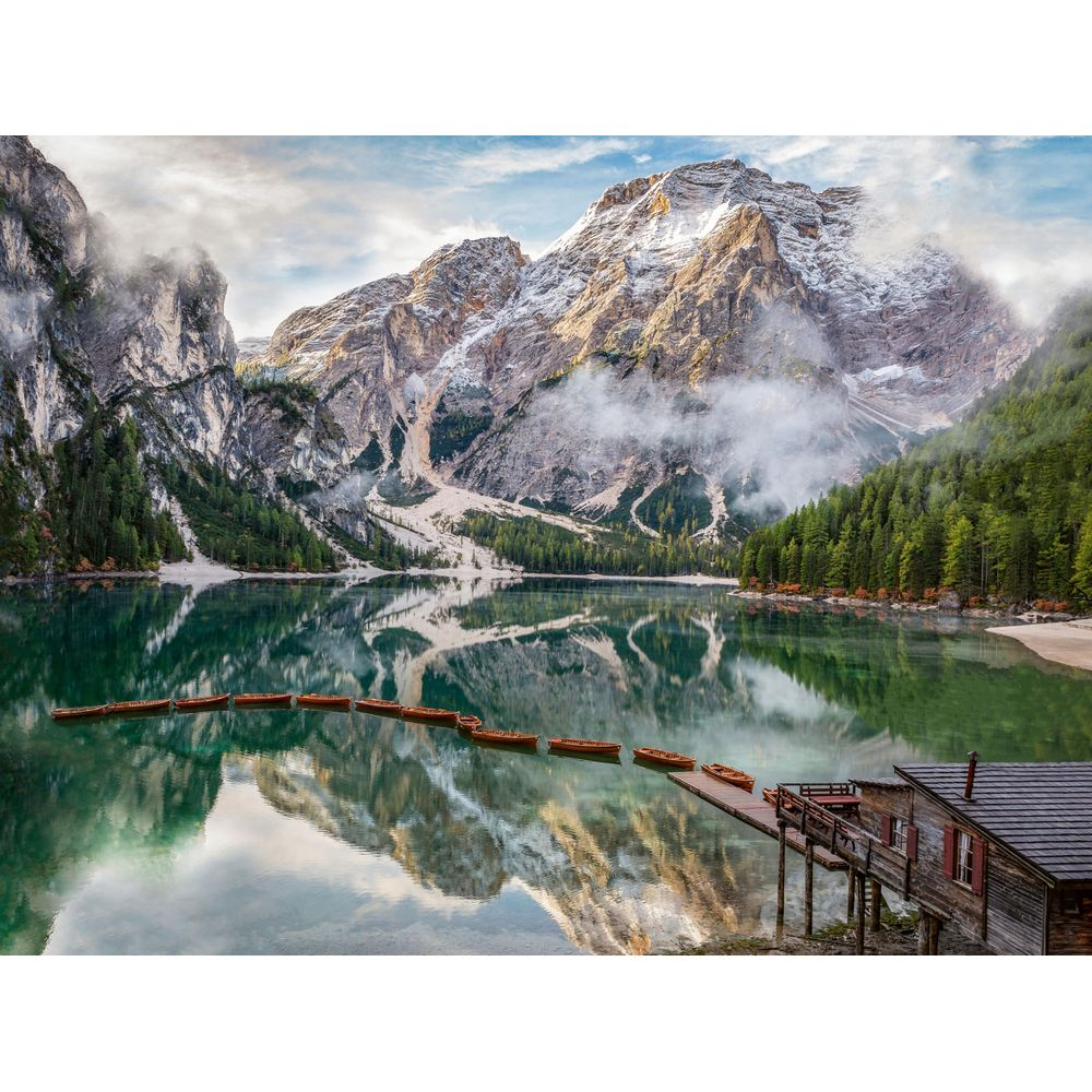 Un sereno lago di montagna con file di barche a remi e una rimessa in legno.