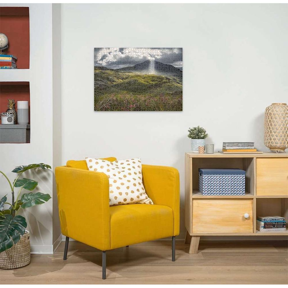 Gelber Sessel mit Tupfenkissen vor Holzschrank. Landschaftspuzzle hängt an der Wand.