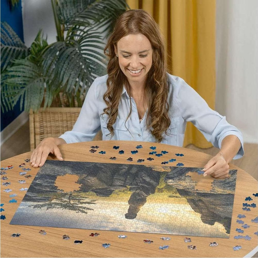 Donna al tavolo rotondo che assembla un puzzle di paesaggio. Luce dell'ora d'oro.