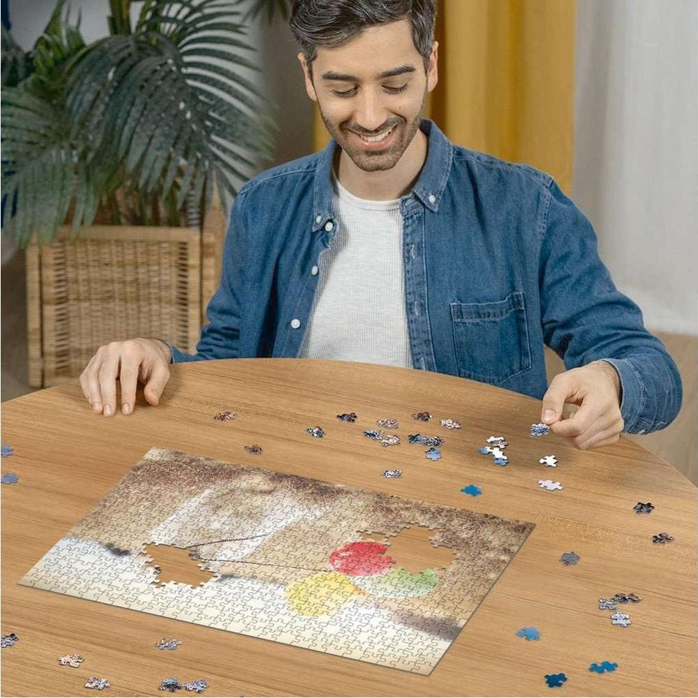 Un uomo assembla un puzzle di una foglia rossa su un tavolo di legno.