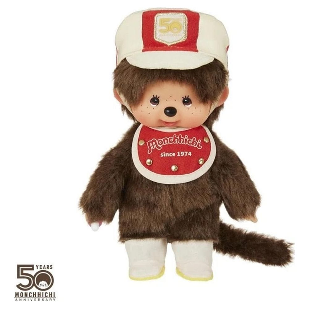 Un Monchhichi con pelliccia marrone, bavaglino rosso e cappellino bianco/rosso.