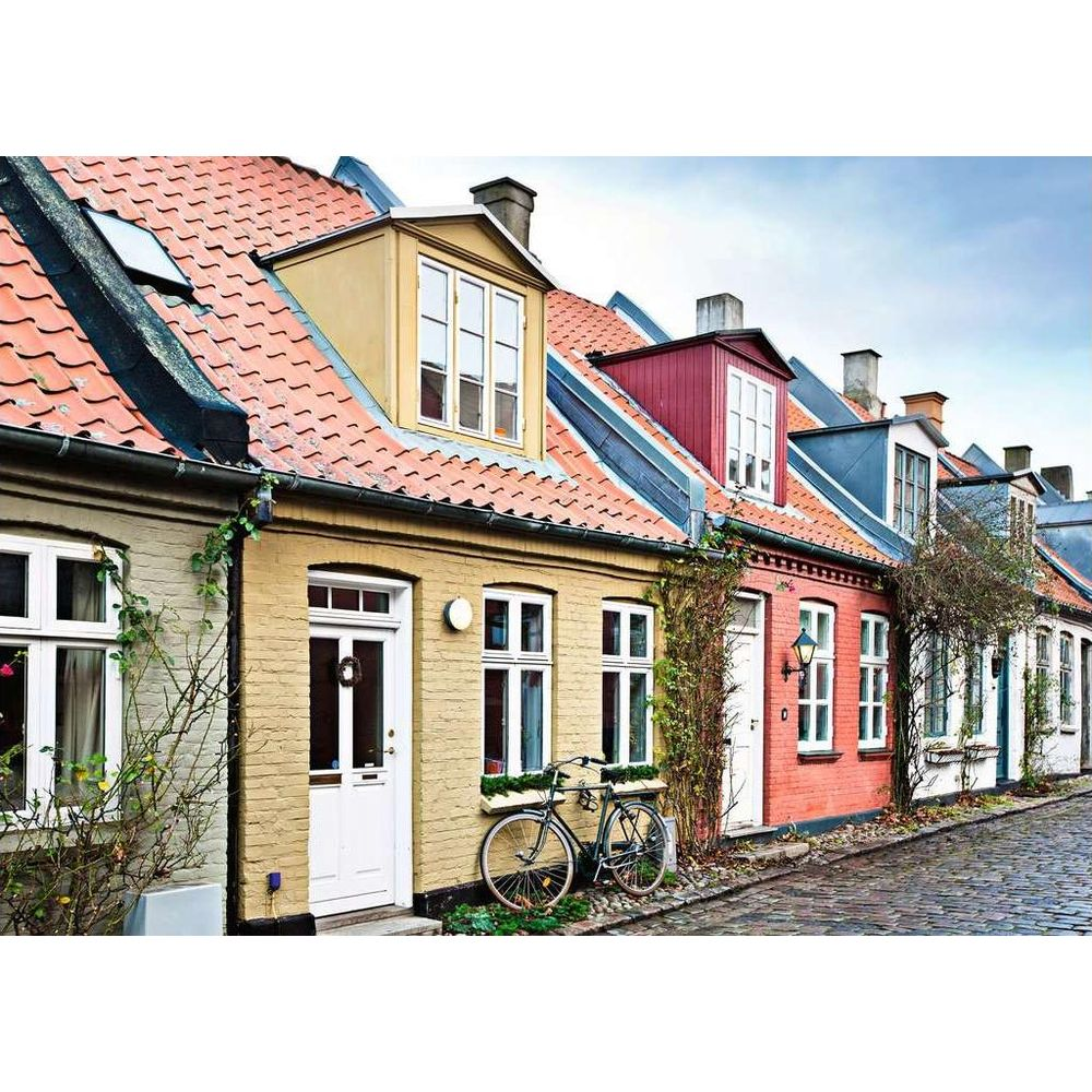 Reihe bunter Häuser mit roten Ziegeldächern und Kopfsteinpflasterstraße.