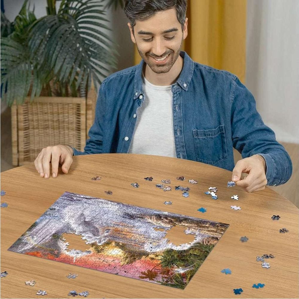 Mann setzt Puzzleteil mit Berglandschaft und Sonnenuntergang zusammen.