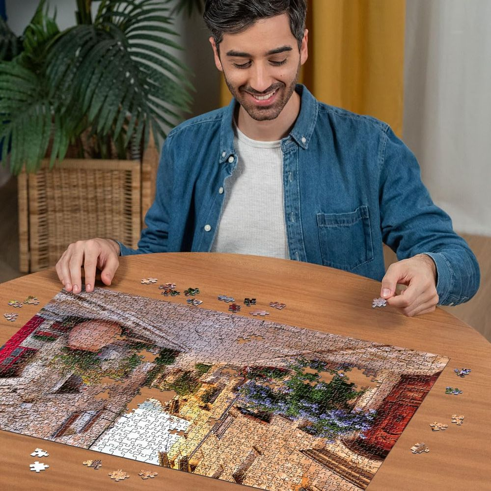 Uomo in camicia blu compone un puzzle di tetto in pietra.