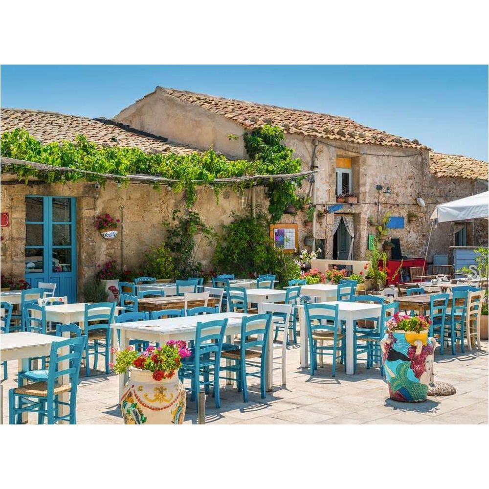 Un ristorante all'aperto con sedie blu e tavoli bianchi sotto le viti.