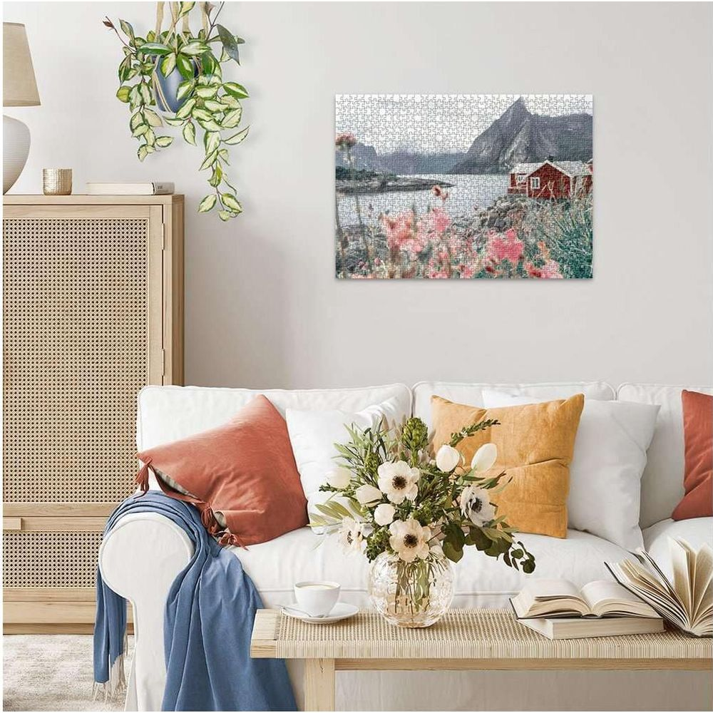 Un puzzle montre une maison rouge au bord d'un lac avec des montagnes. Fleurs au premier plan.