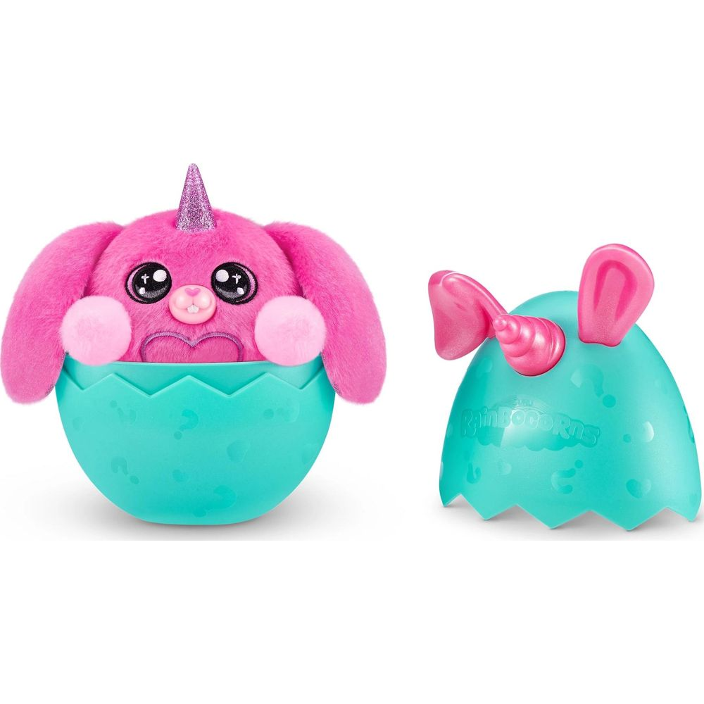 Un peluche unicorno rosa in un uovo blu e un altro uovo con orecchie e corno.