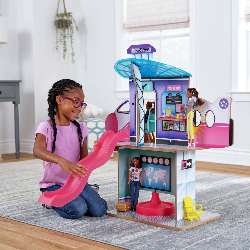 Une fille joue avec un set de jeu d'aéroport avec des poupées et un toboggan.