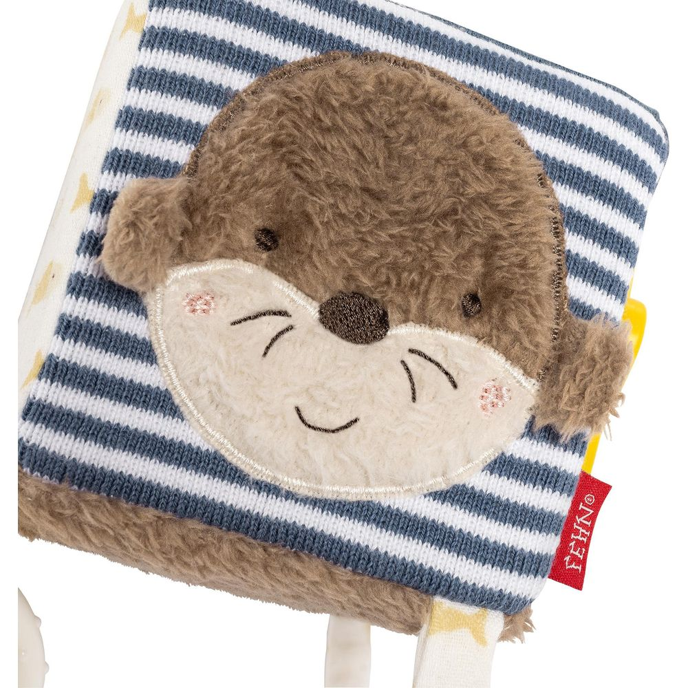 Ein weiches Stoffbuch mit einem Ottergesicht in Streifen.