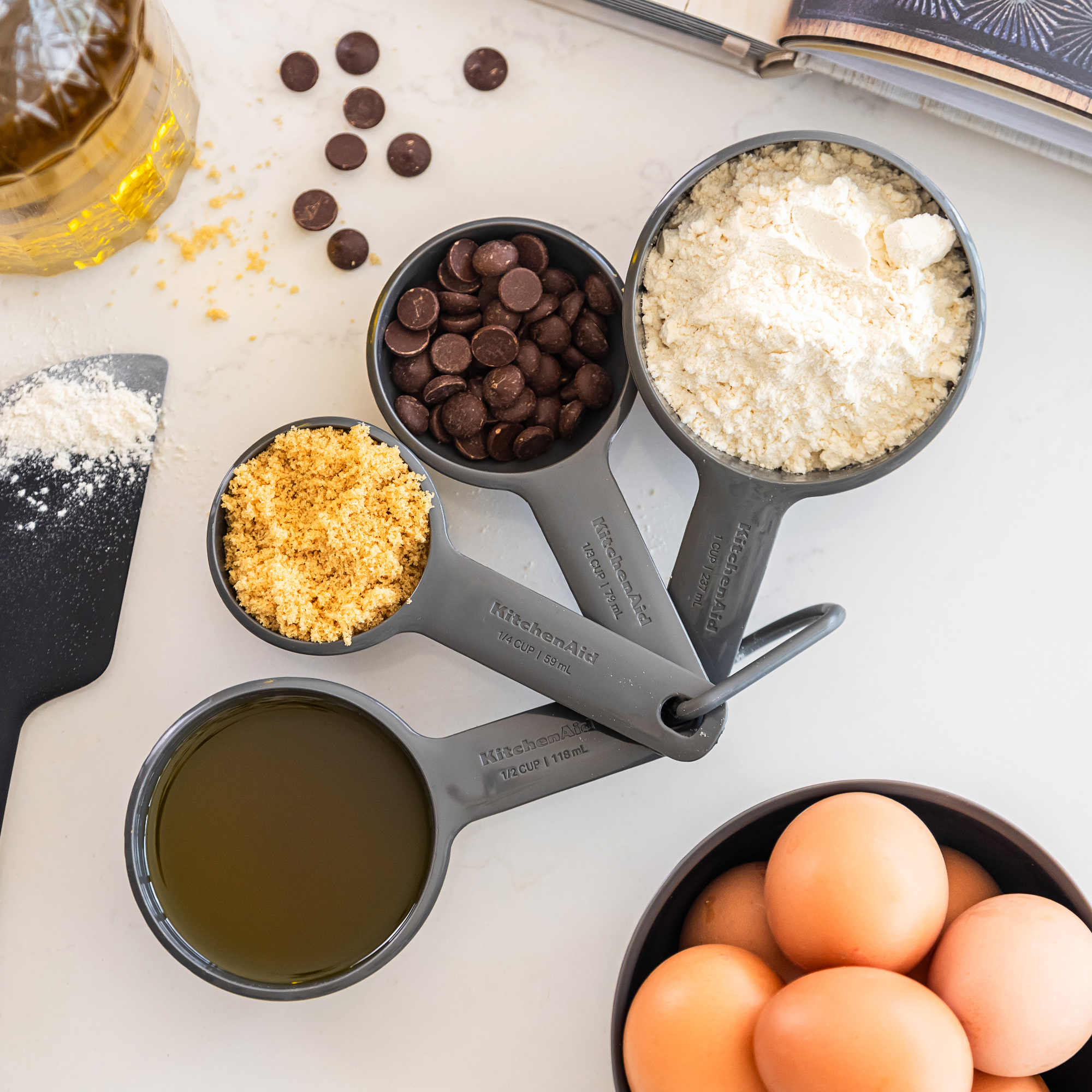 Messbecher mit Mehl, braunem Zucker, Schokostückchen, Öl und Eiern.