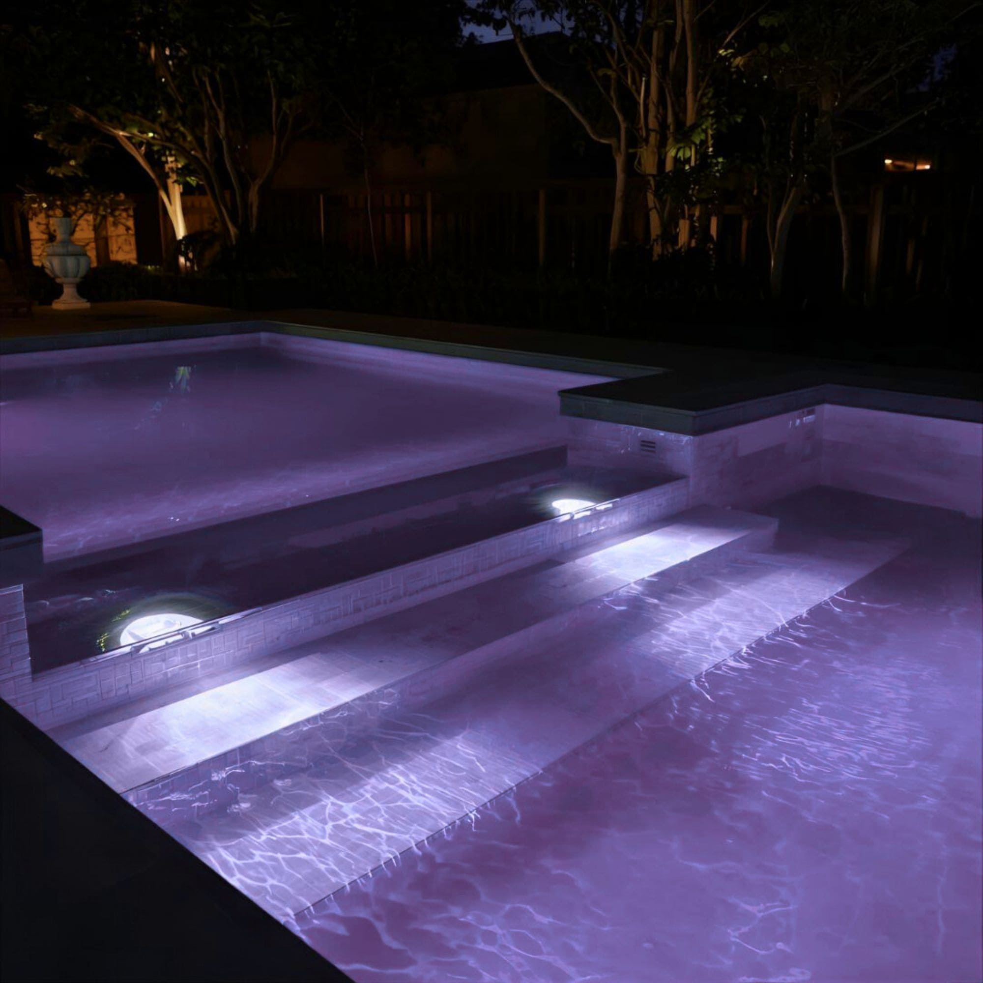 Una piscina iluminada con agua morada y escalones por la noche.