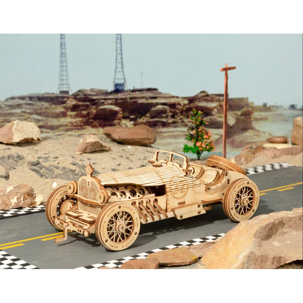 Ein Holzmodell eines Oldtimer-Rennwagens auf einer Straße mit Ziellinie.
