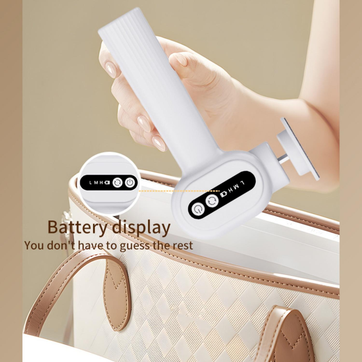 Eine Hand hält ein weißes Gerät mit Batteriestatusanzeige über einer Tasche.