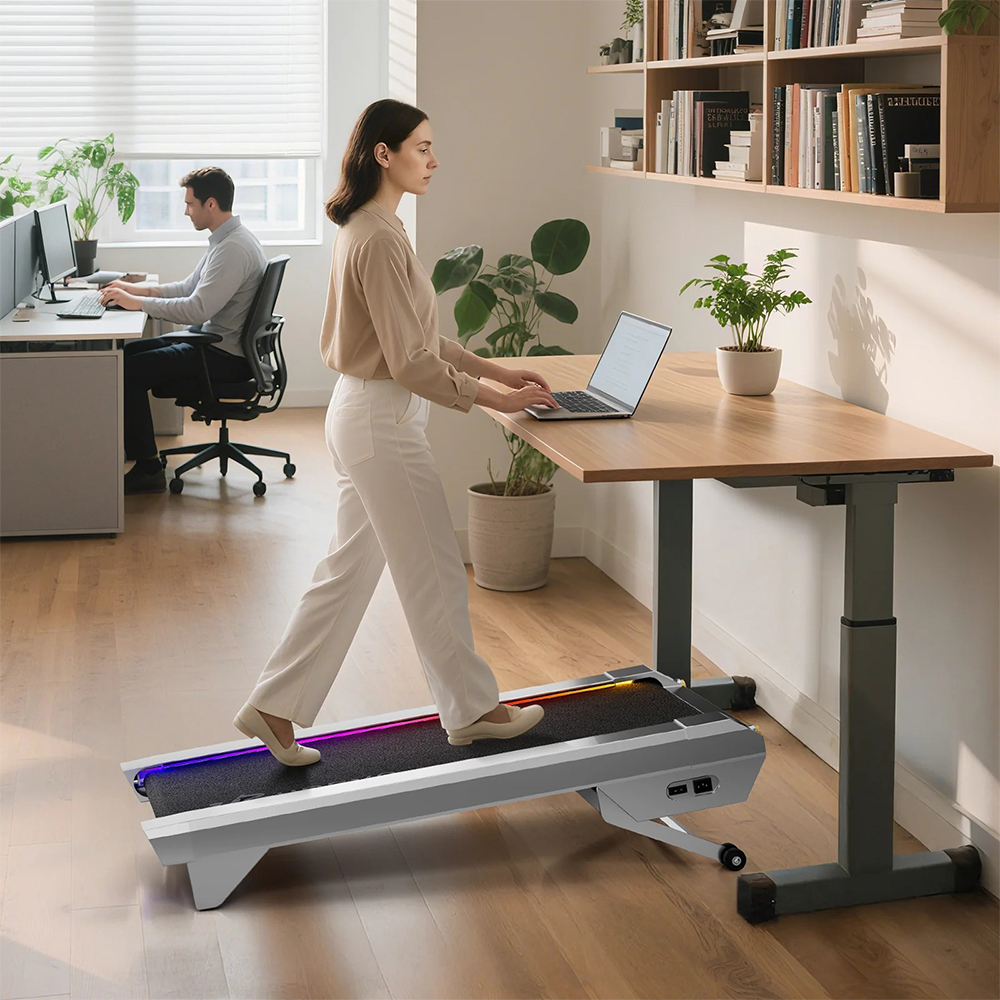 Kobieta idzie na bieżni, pisze na laptopie. Mężczyzna siedzi przy biurku.