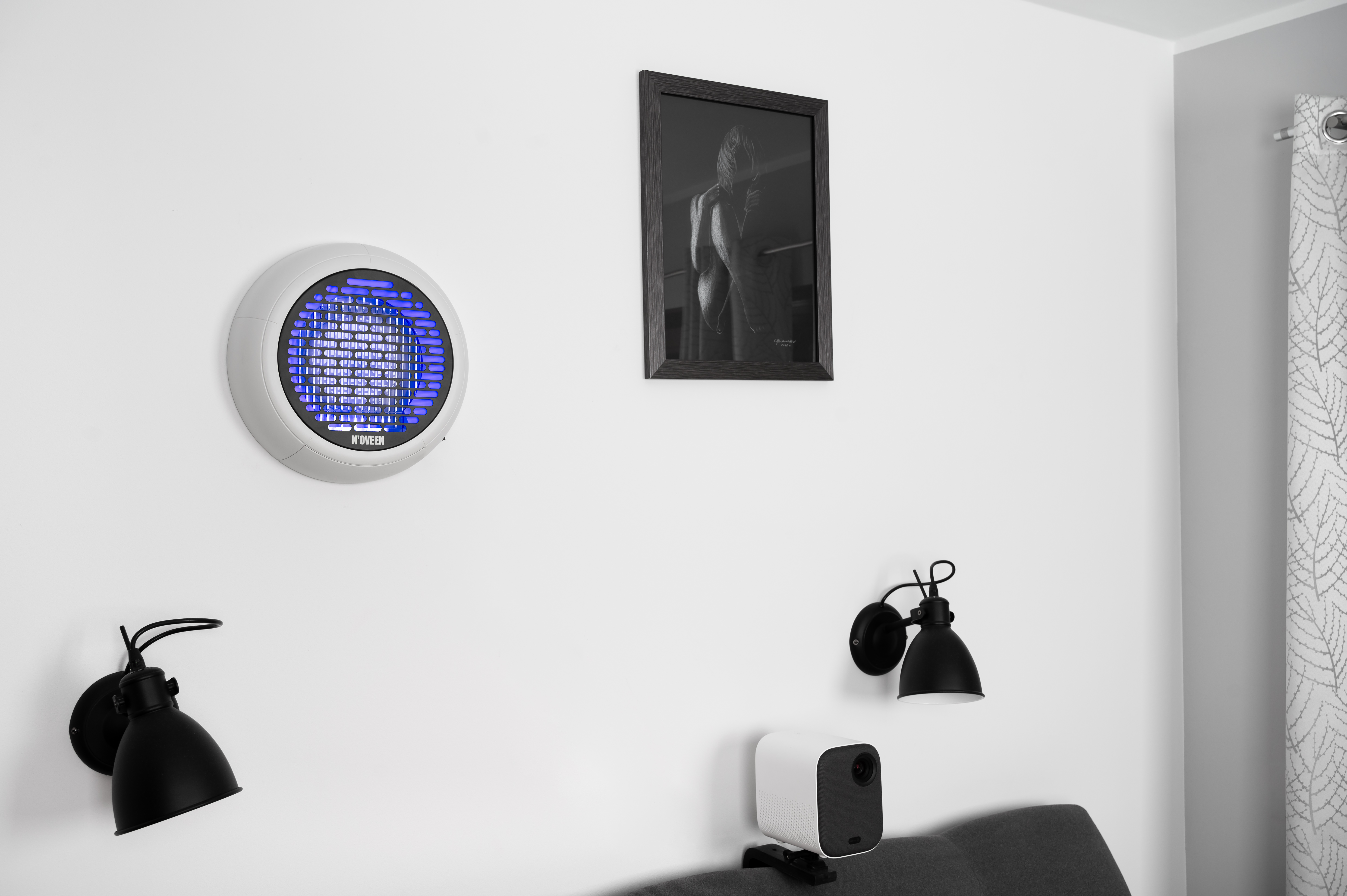 Okrągły wentylator z niebieskimi światłami wisi na ścianie obok czarno-białego zdjęcia.