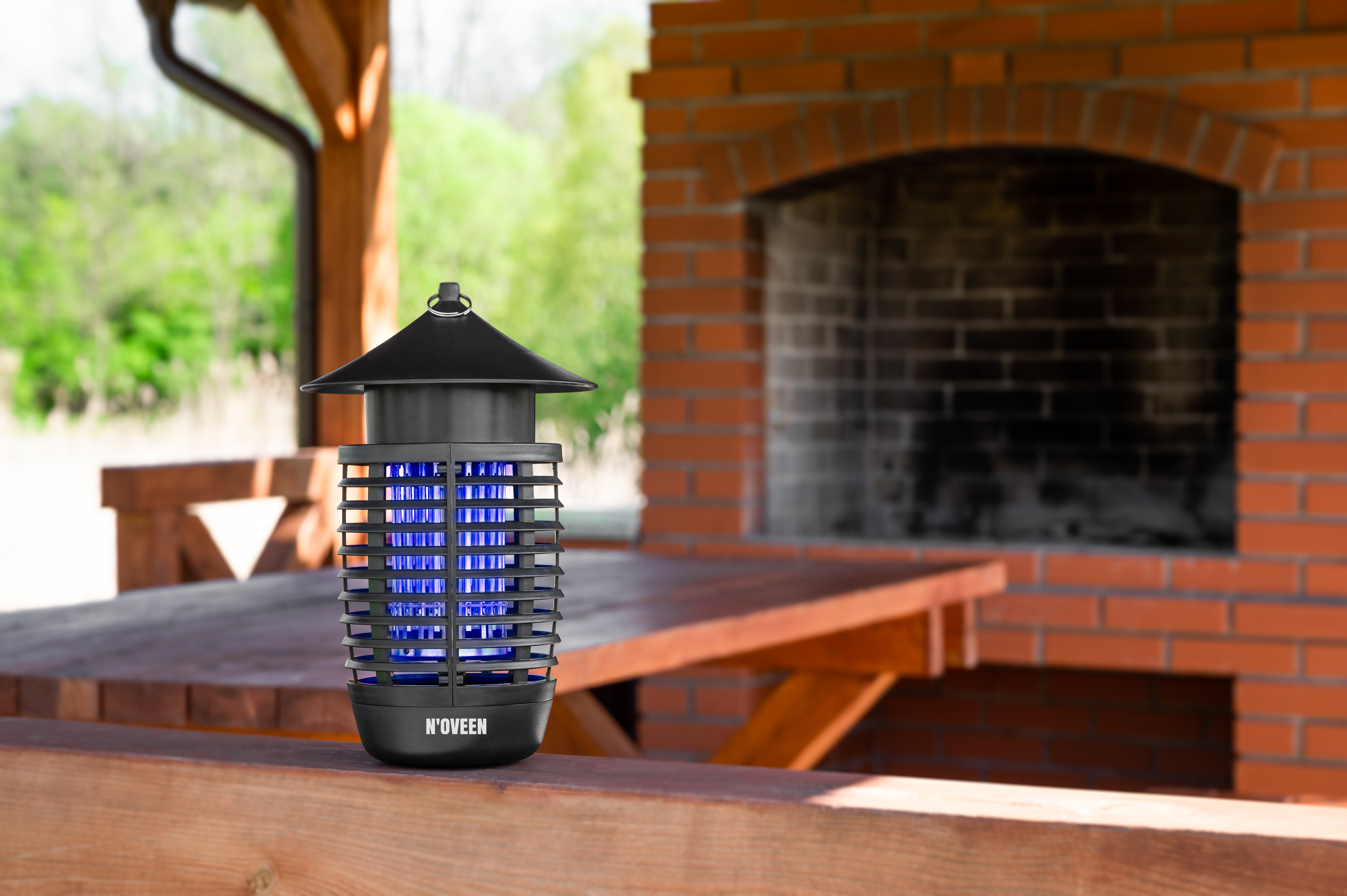 Czarny zabójca owadów z niebieskim światłem UV na drewnianej balustradzie.