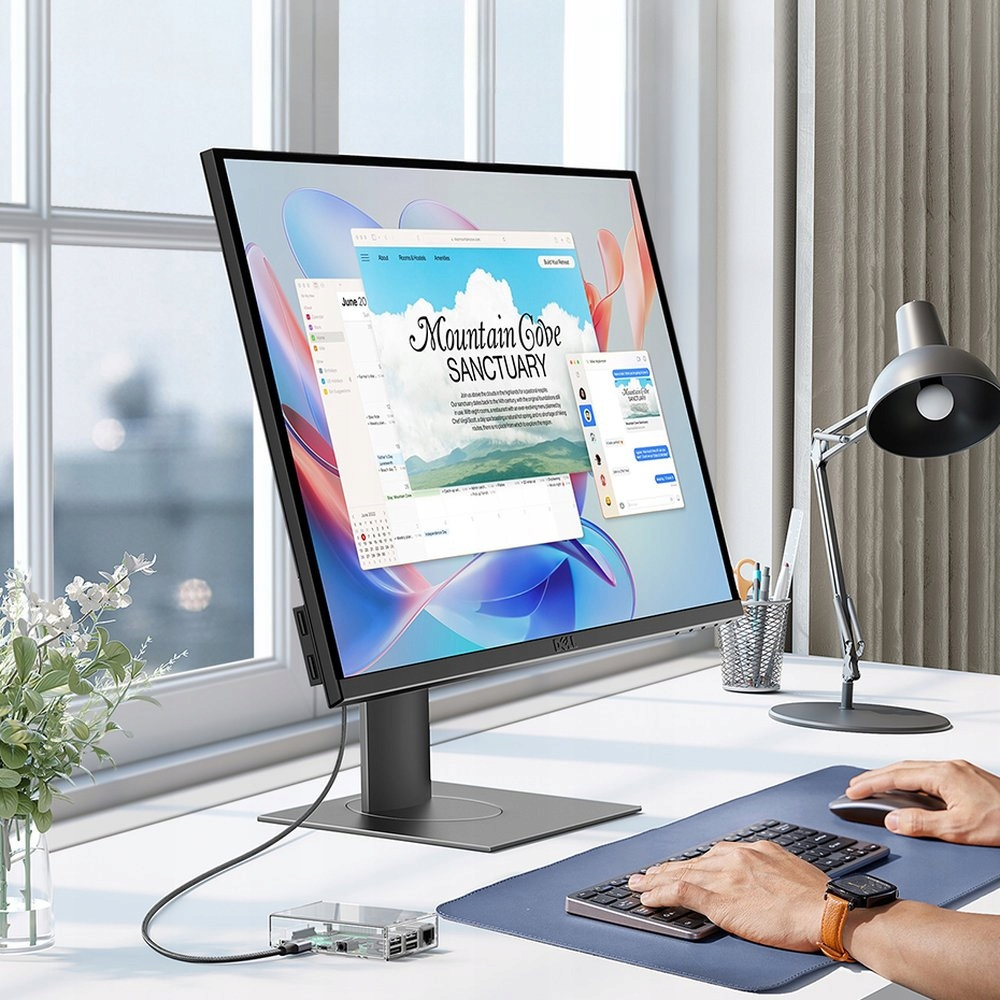 Biurko z monitorem Dell wyświetlającym stronę internetową. Widoczne są również klawiatura, mysz i lampa.