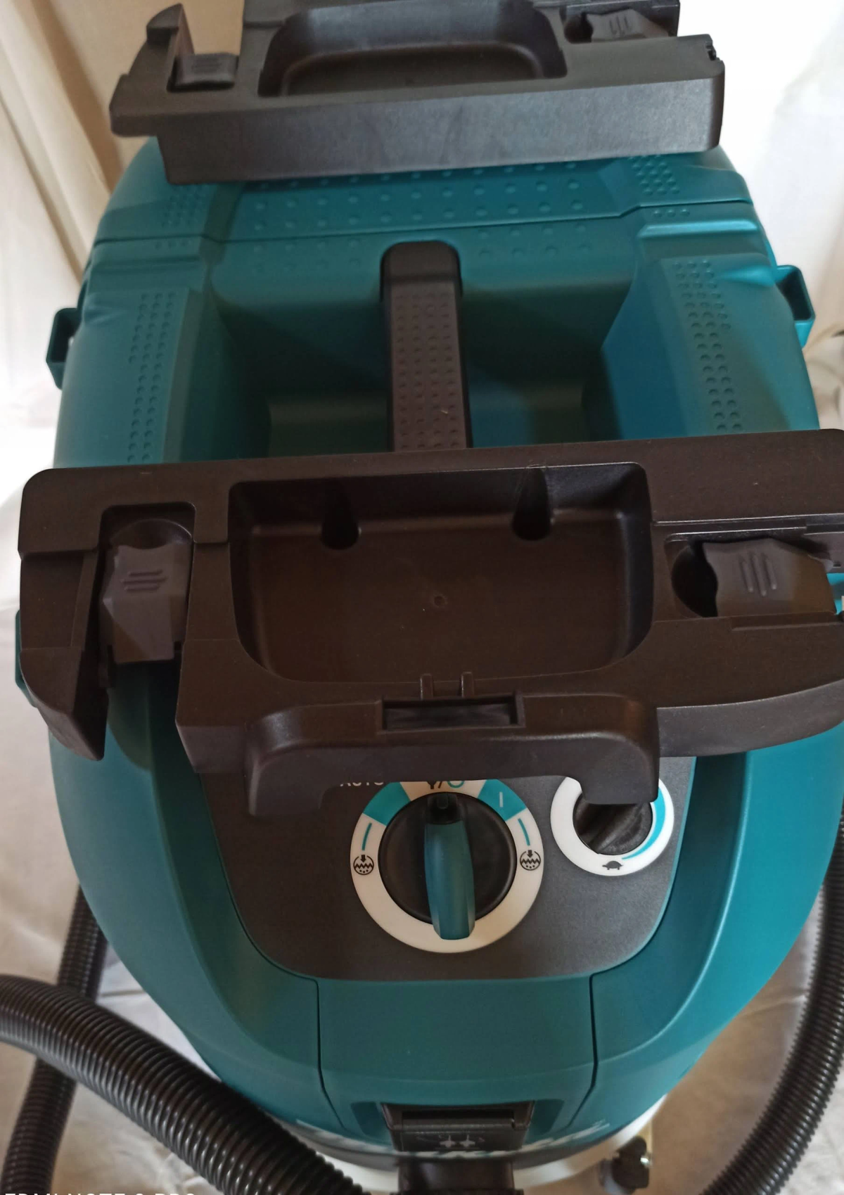 Odkurzacz w kolorze turkusowym z czarnymi akcesoriami i pokrętłami.