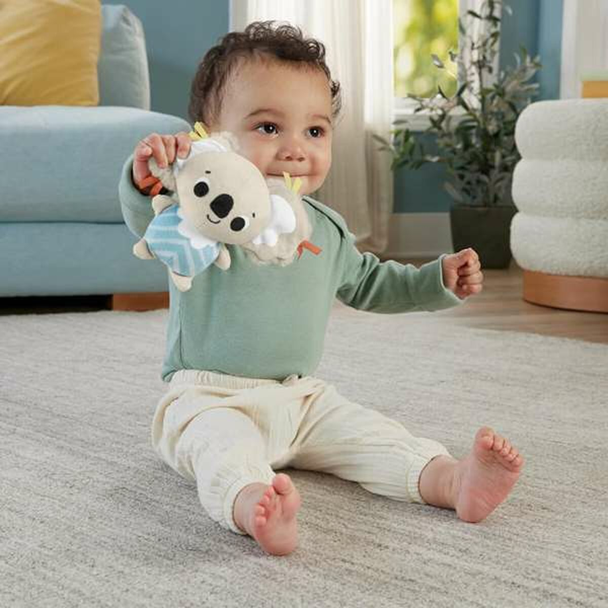 Ein Baby sitzt auf einem Teppich und hält ein Koala-Spielzeug.