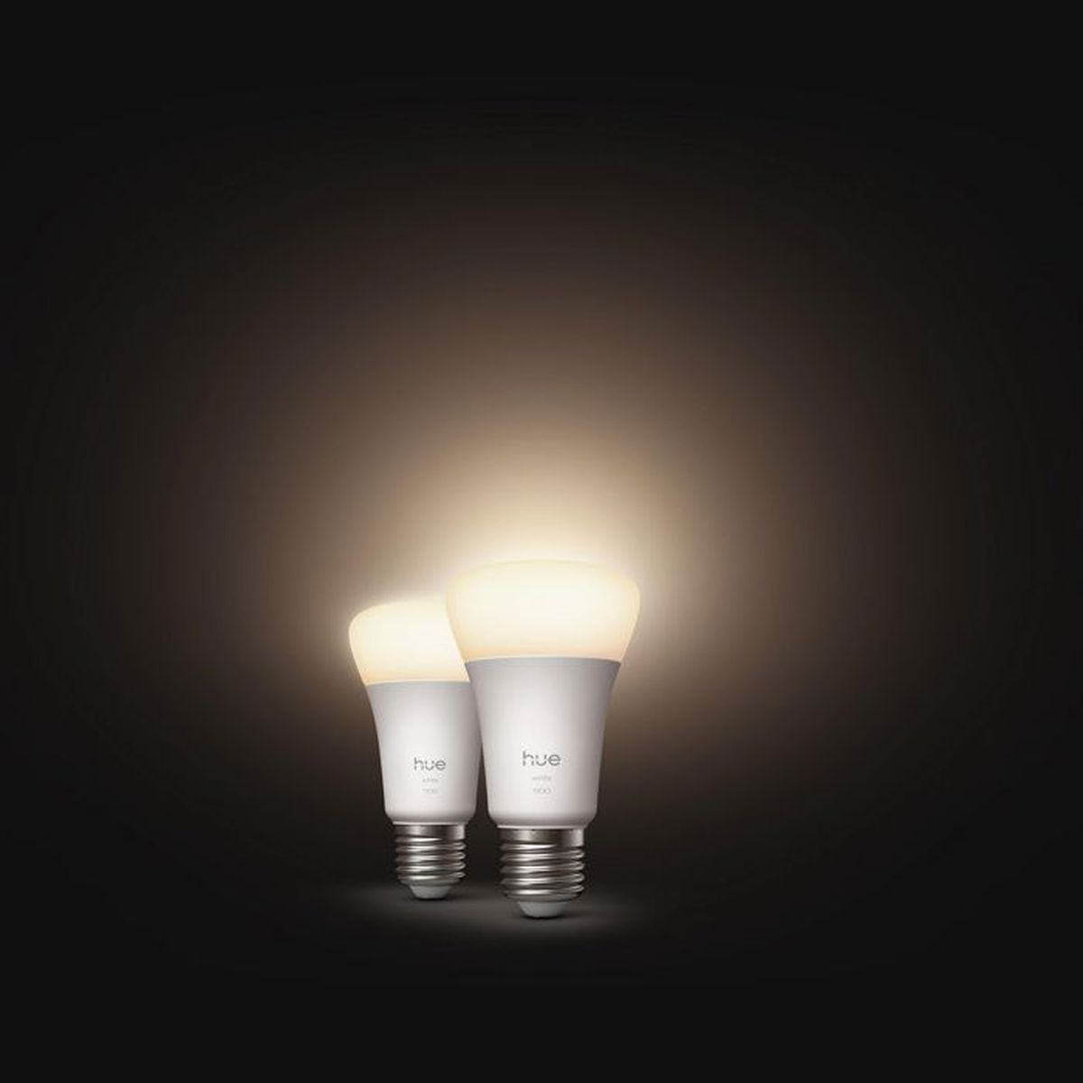 Due lampadine Hue bianche con base a vite brillano su sfondo scuro.