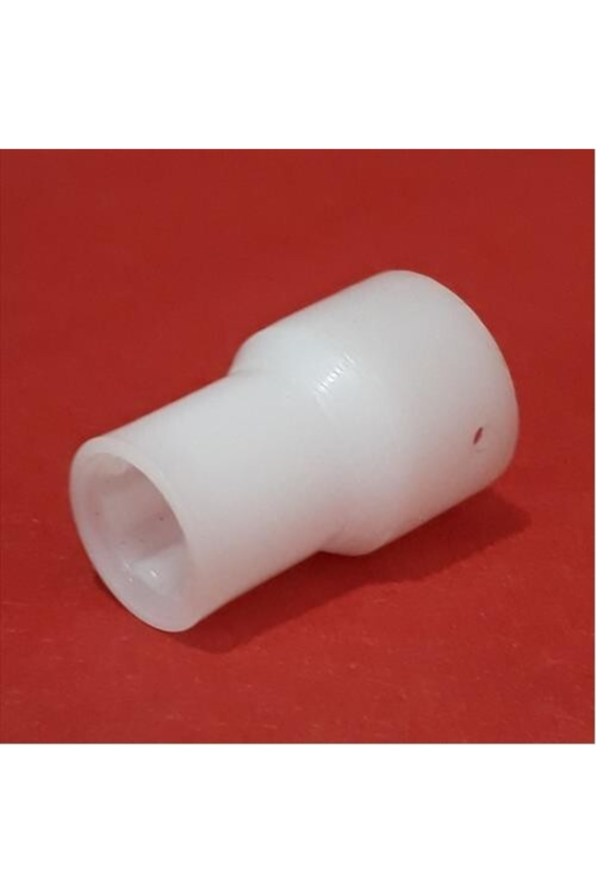 Daha geniş ve daha dar uçlu beyaz plastik parça, kırmızı arka plan üzerinde.