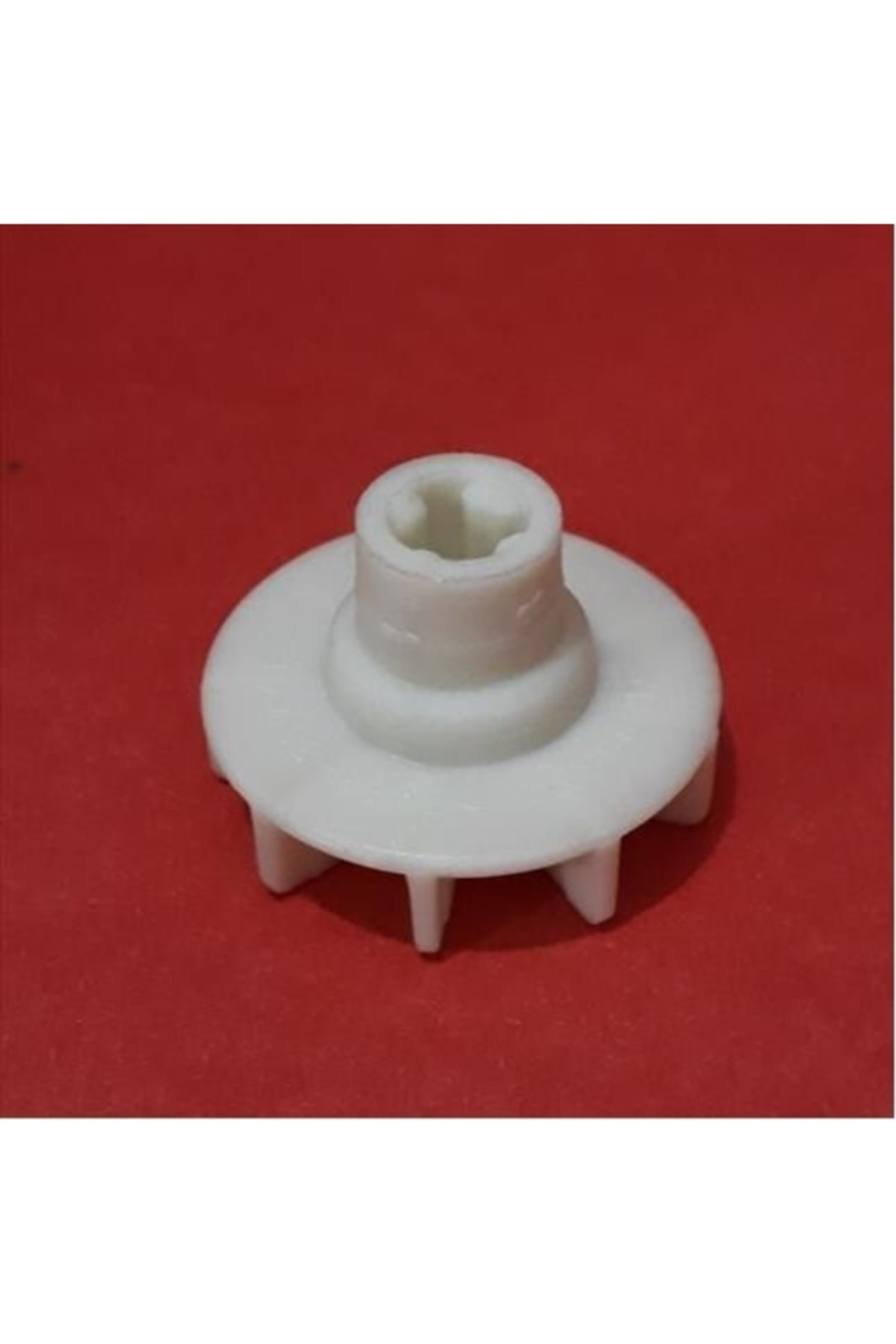 Kırmızı arka plan üzerinde dişli beyaz plastik parça.
