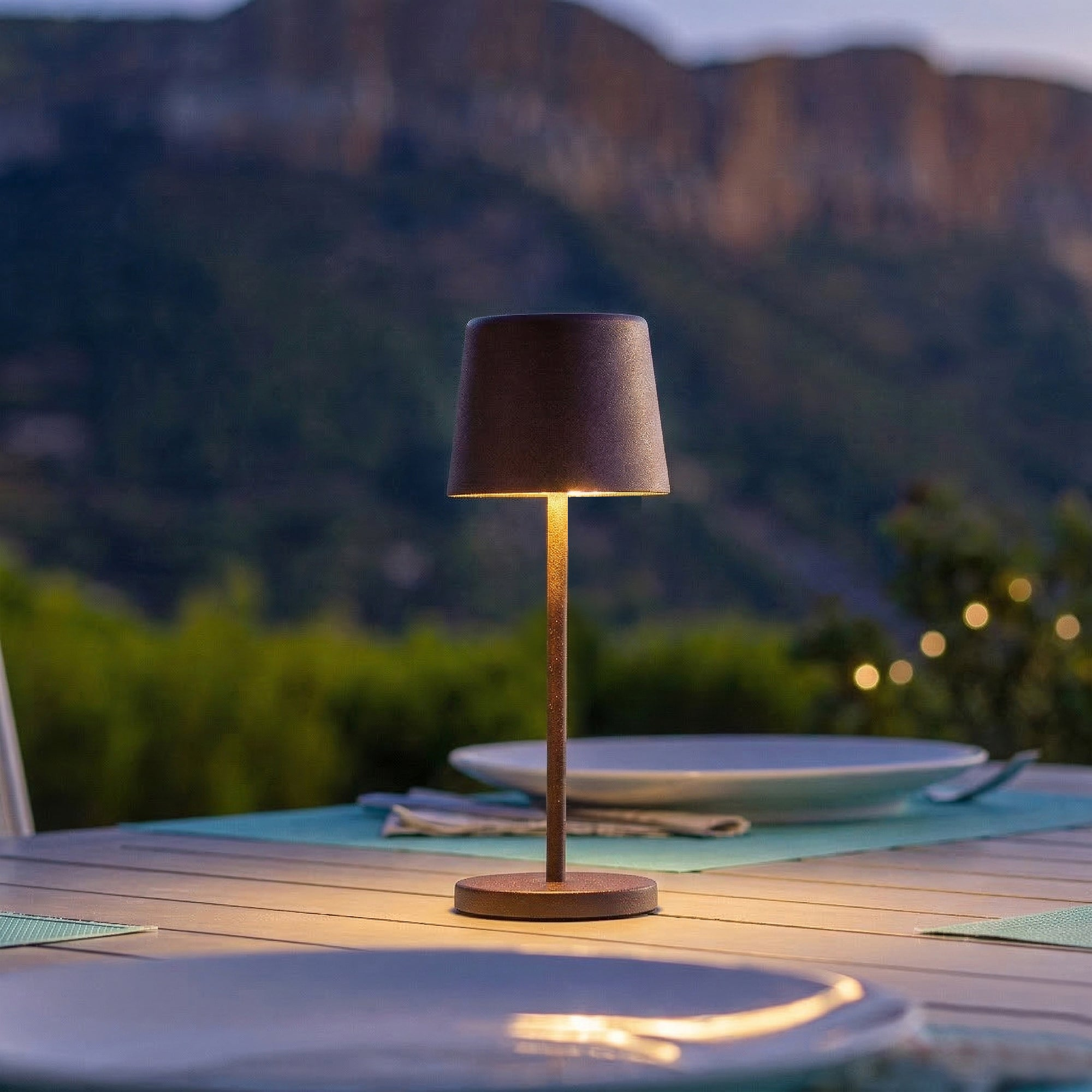 Eine Tischlampe steht auf einem Holztisch mit Blick auf Berge.