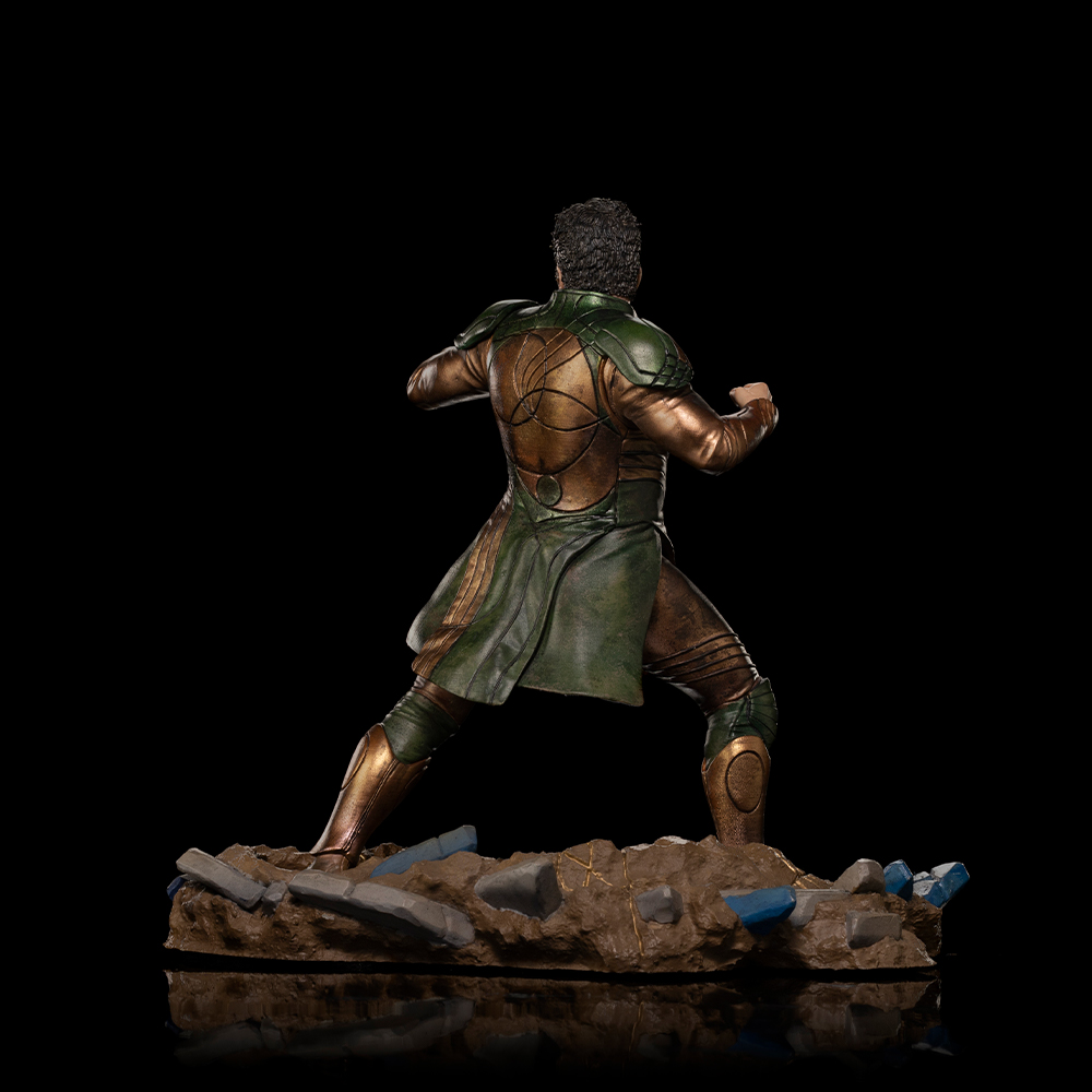 Una figura in armatura verde e oro sta sulle rocce.