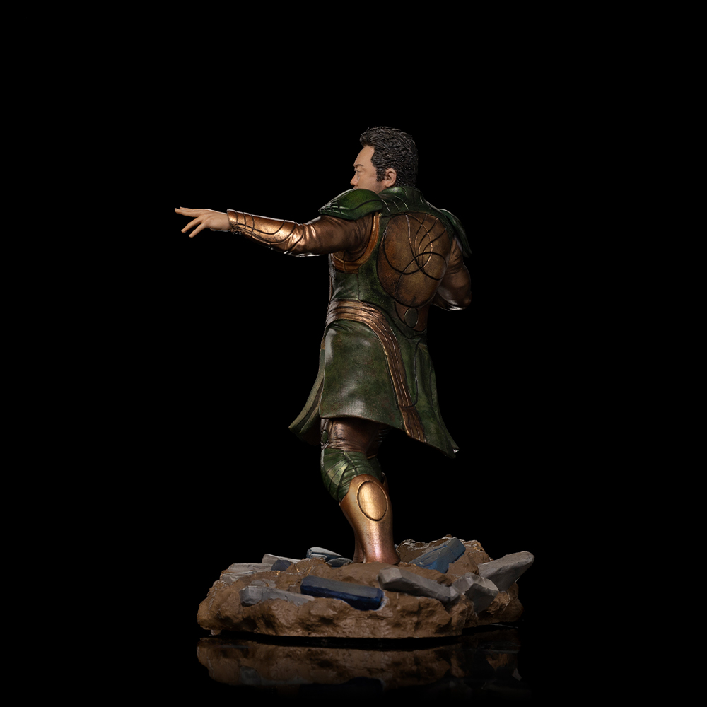 Uomo in armatura verde con accenti dorati, posato su terreno roccioso.