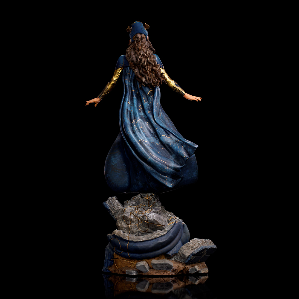Statua di donna in mantello blu con accenti dorati su base rocciosa.