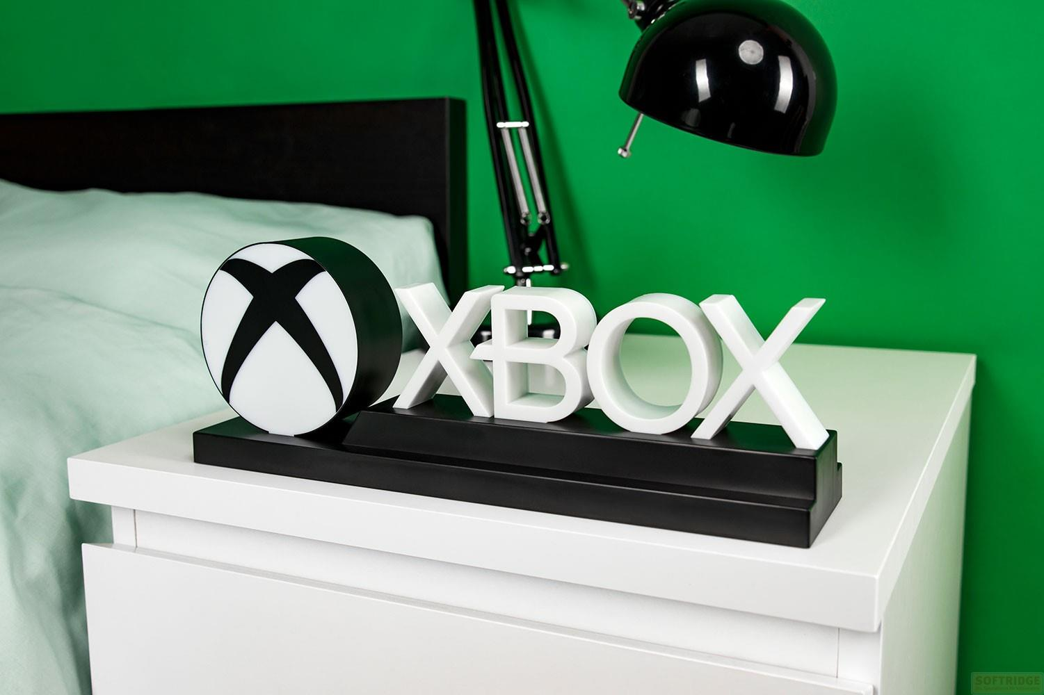 Xbox-Logo-Dekoration auf einem weißen Nachttisch, grüne Wand im Hintergrund.
