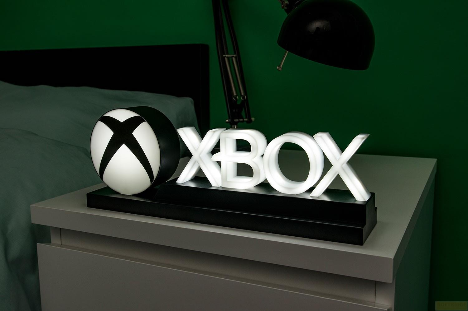 Ein leuchtendes Xbox-Logo und ein Xbox-Symbol stehen auf einem Nachttisch.