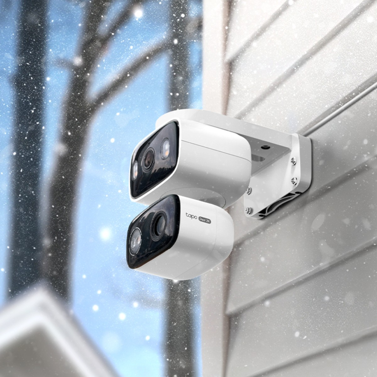 Dwie białe kamery zamontowane na ścianie domu podczas opadów śniegu.