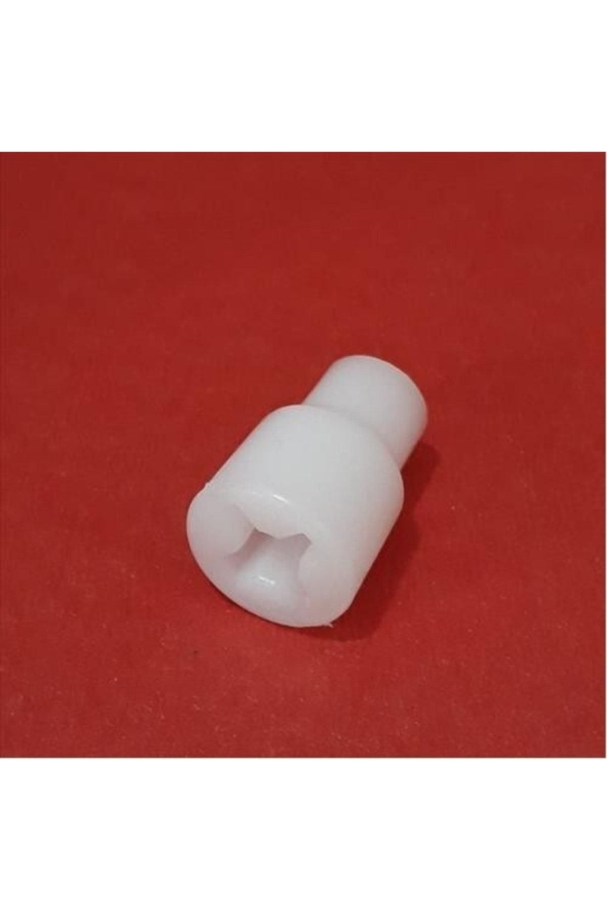 Kırmızı arka plan üzerinde yıldız şeklinde oyuğa sahip beyaz plastik parça.
