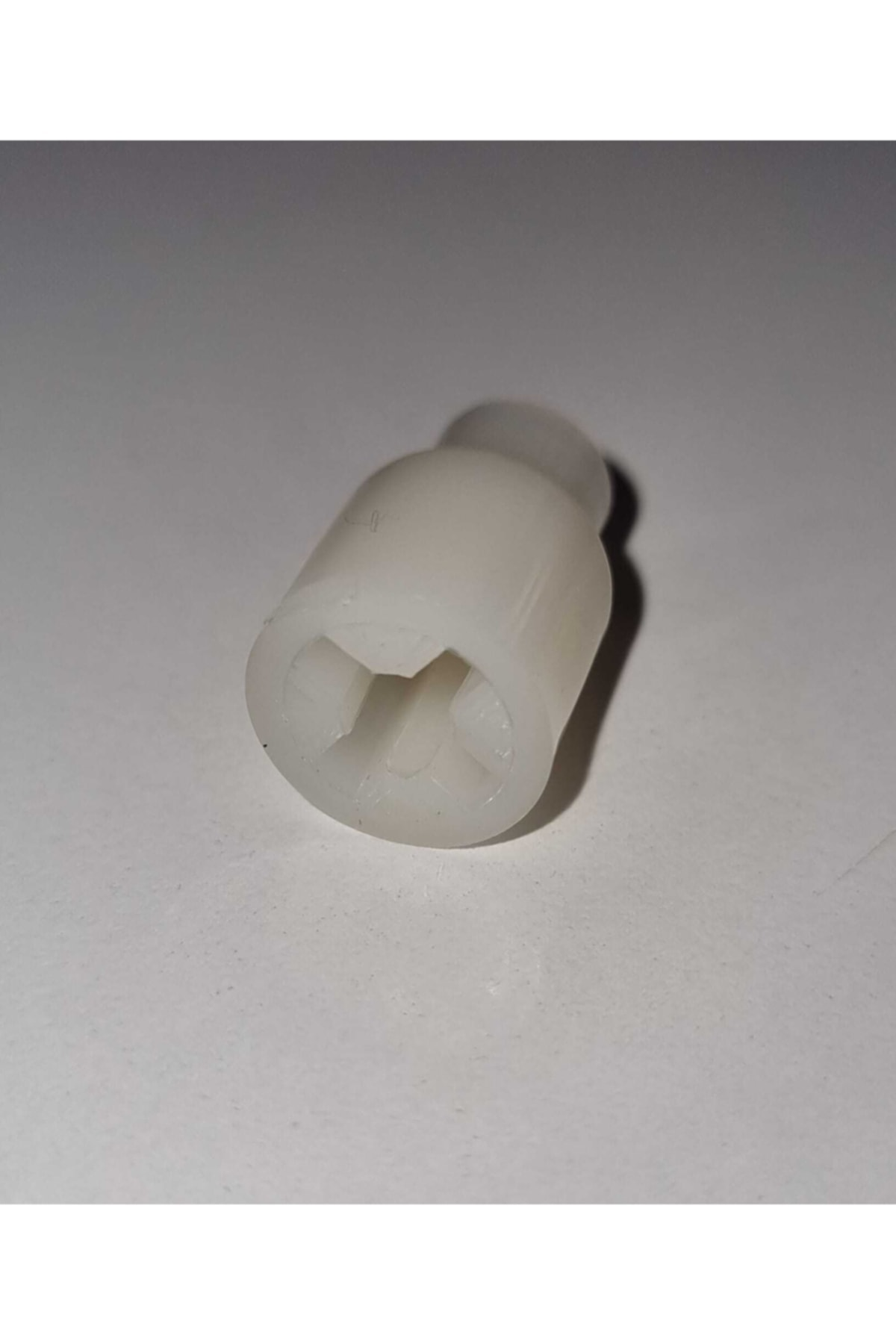 Beyaz plastik, haç şeklinde girintili konektör beyaz yüzeyde duruyor.