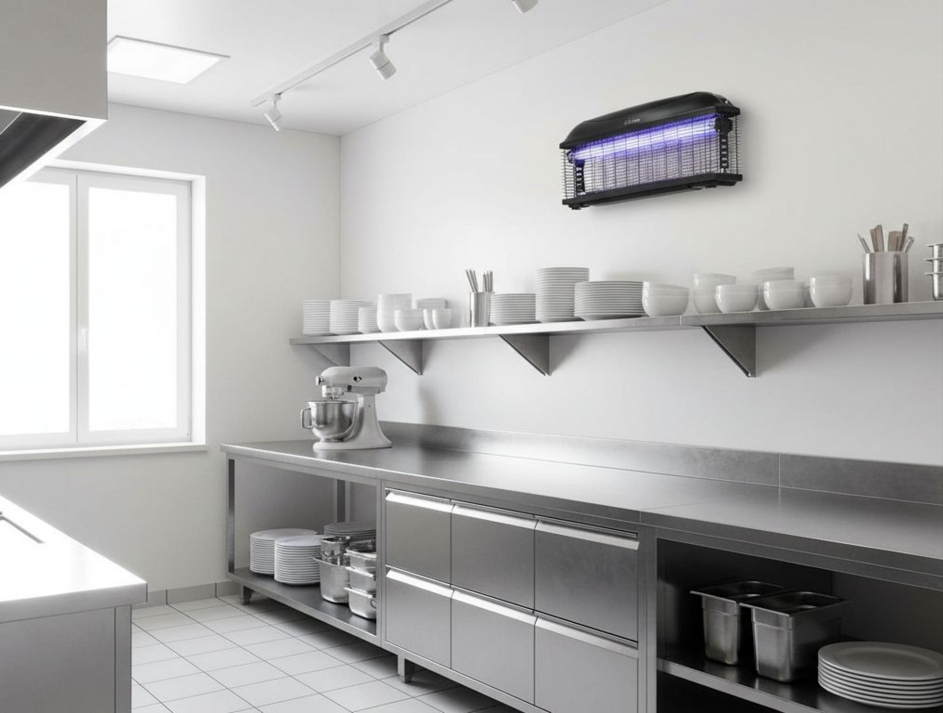 Un área de cocina profesional con superficies de acero inoxidable y un mata insectos.