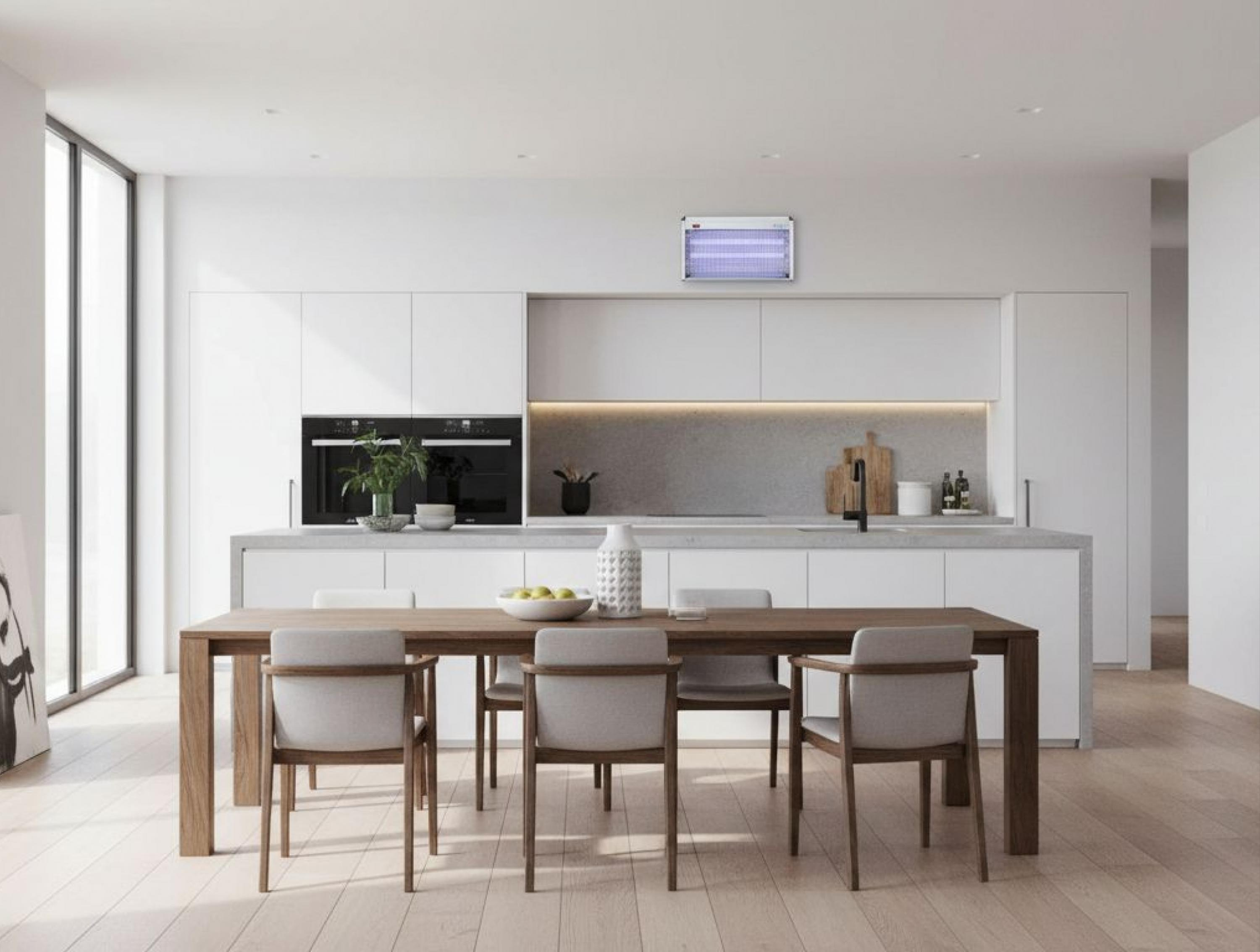 Cocina moderna con comedor, gabinetes blancos, horno doble y mesa de comedor.