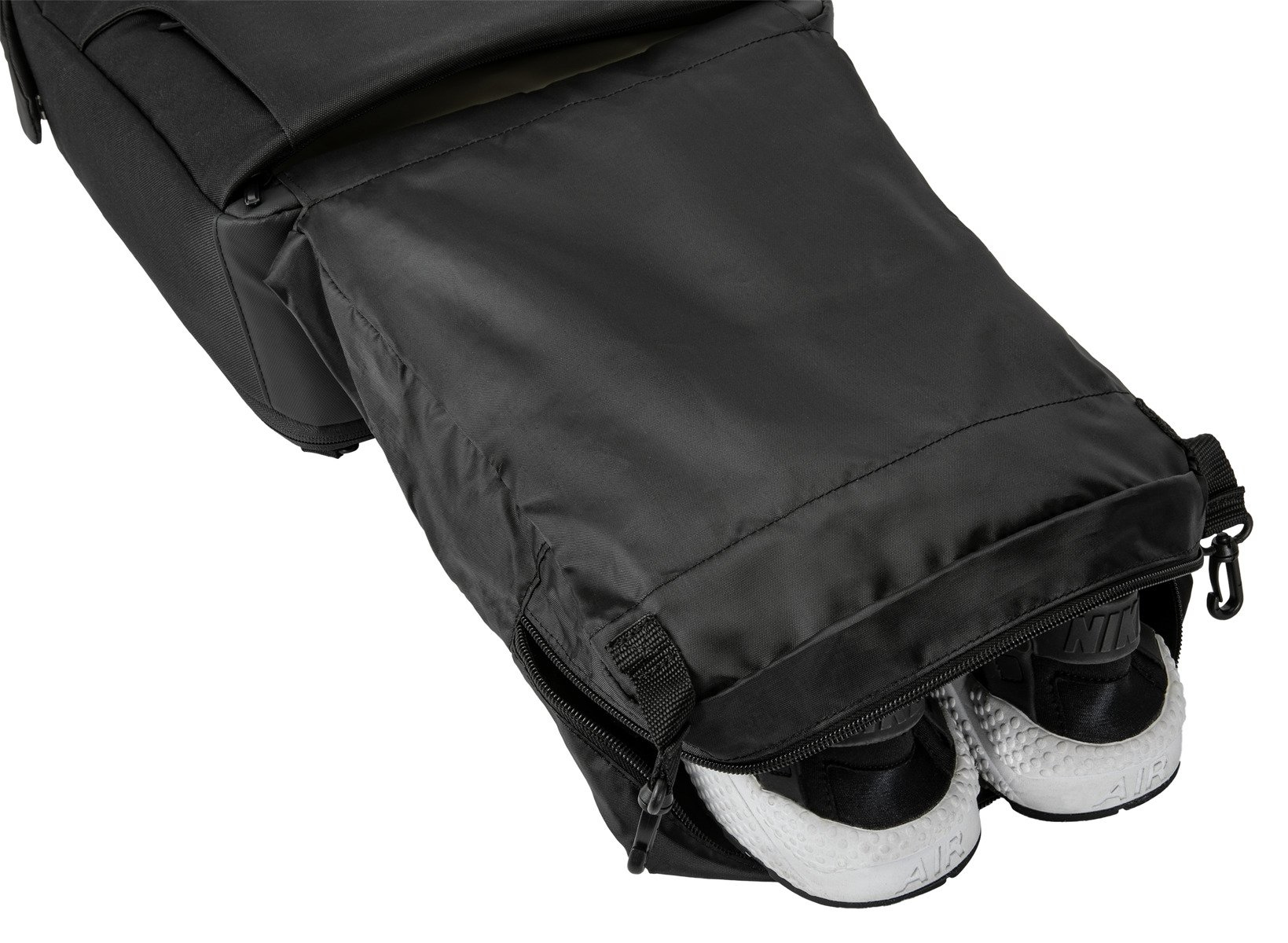 Ein schwarzer Rucksack mit weißen Turnschuhen, die aus einem offenen Fach herausragen.