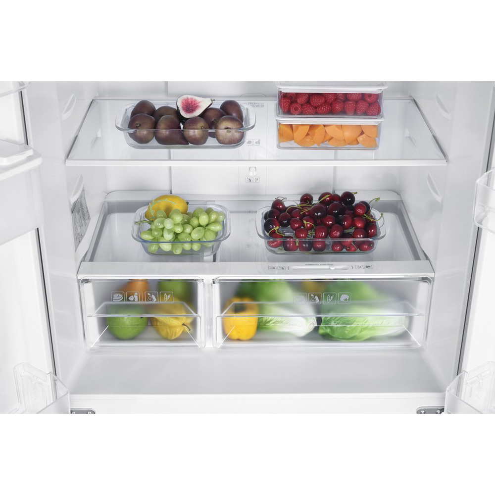 A refrigerator shelf with various fruits and vegetables including plums, berries, grapes, cherries, apples, and lettuce.