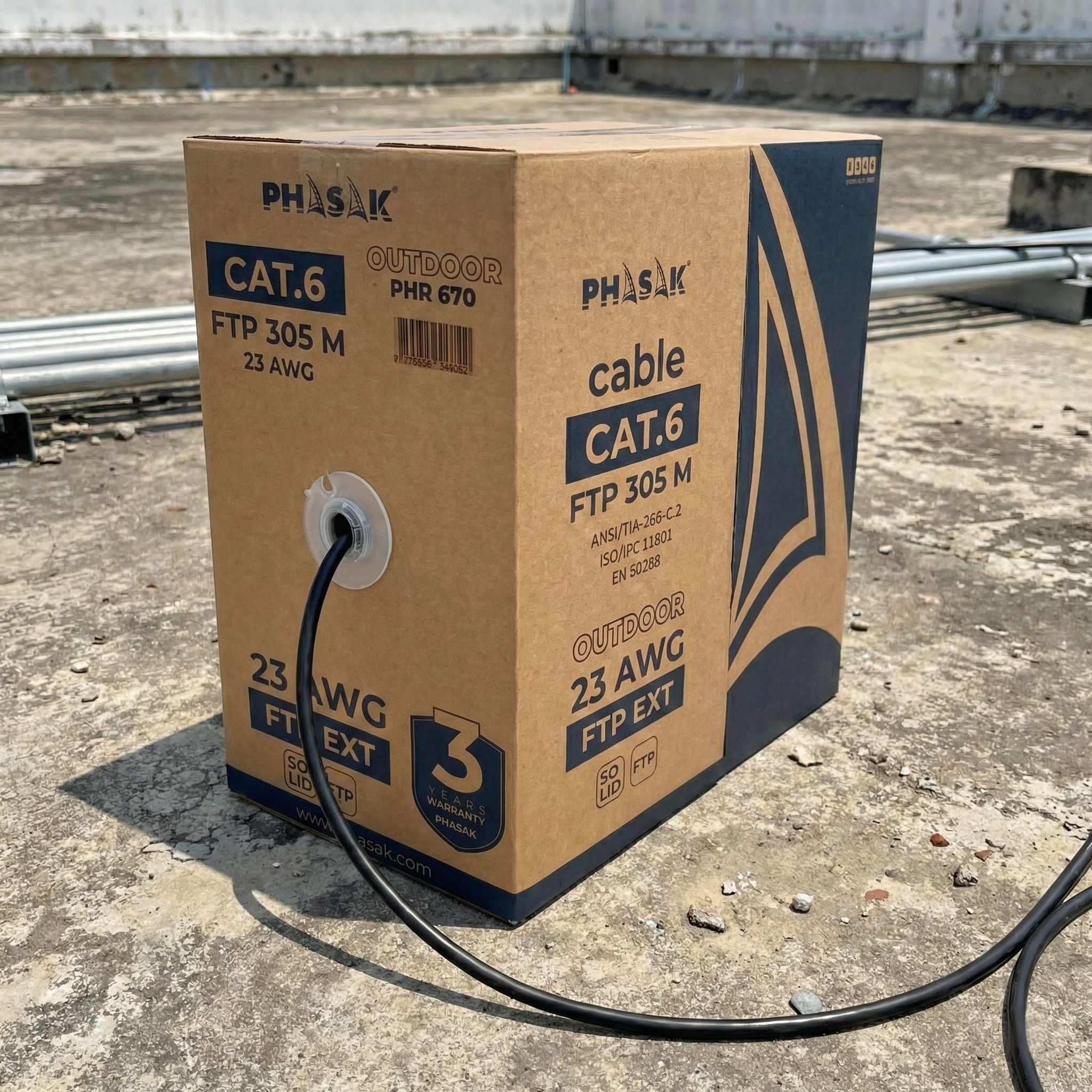 Una scatola di cavi marrone etichettata CAT.6 FTP 305M 23 AWG è all'aperto.