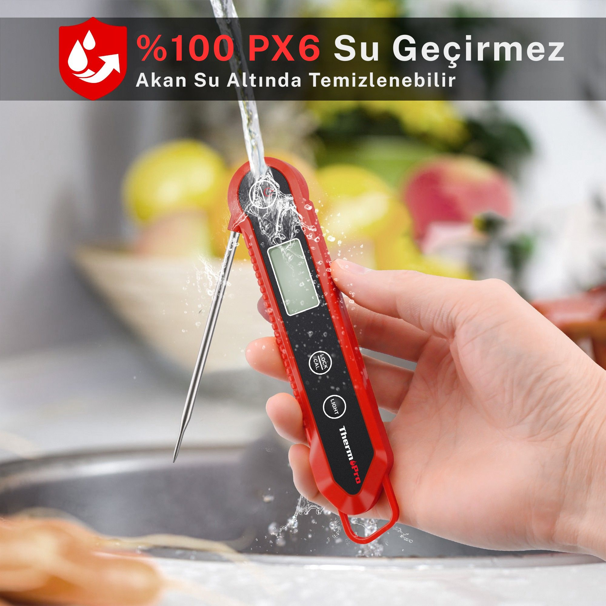Kırmızı termometre akan su altında temizleniyor. Bulanık meyve arka planı.