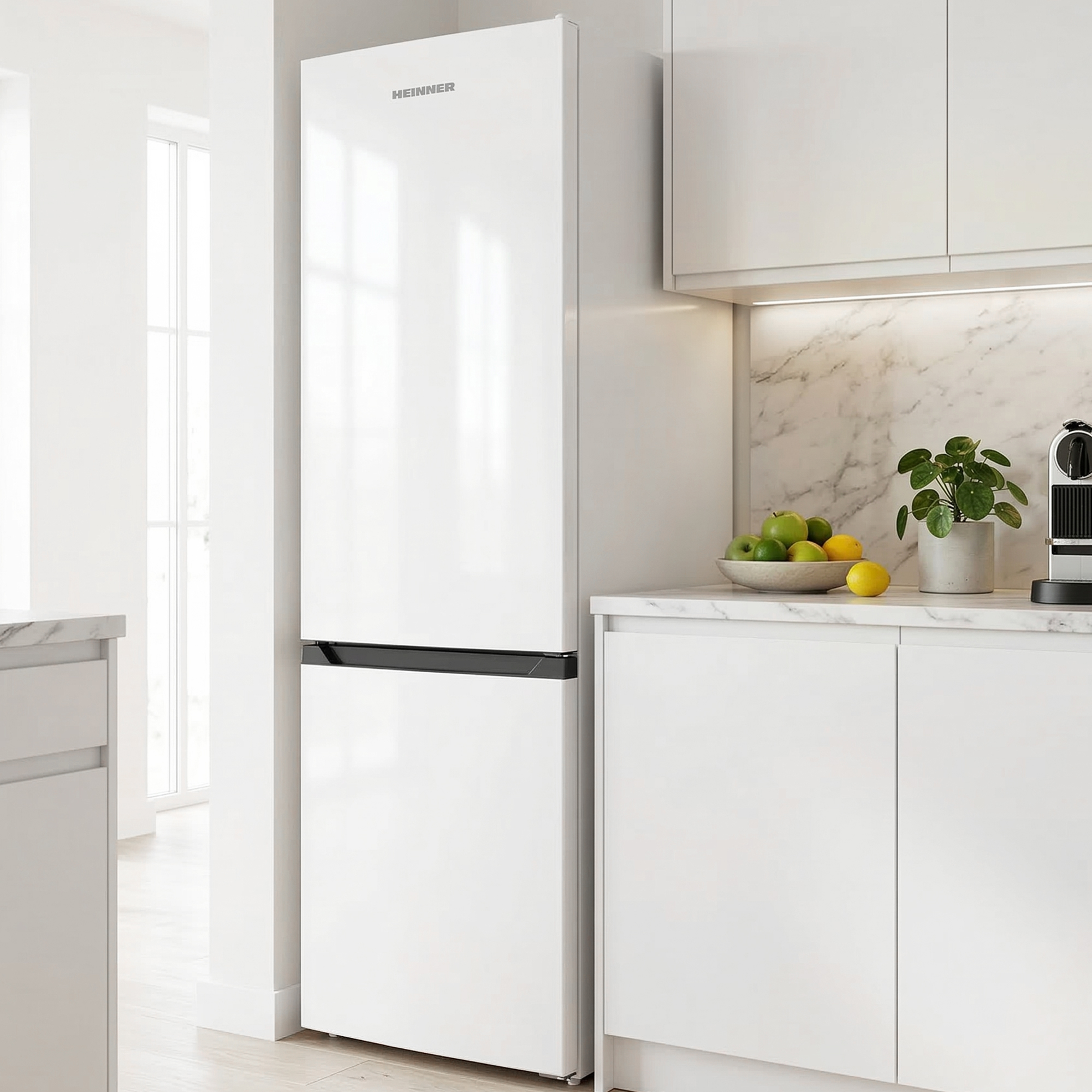 Een moderne witte koelkast in een lichte keuken met marmeren aanrechtblad.