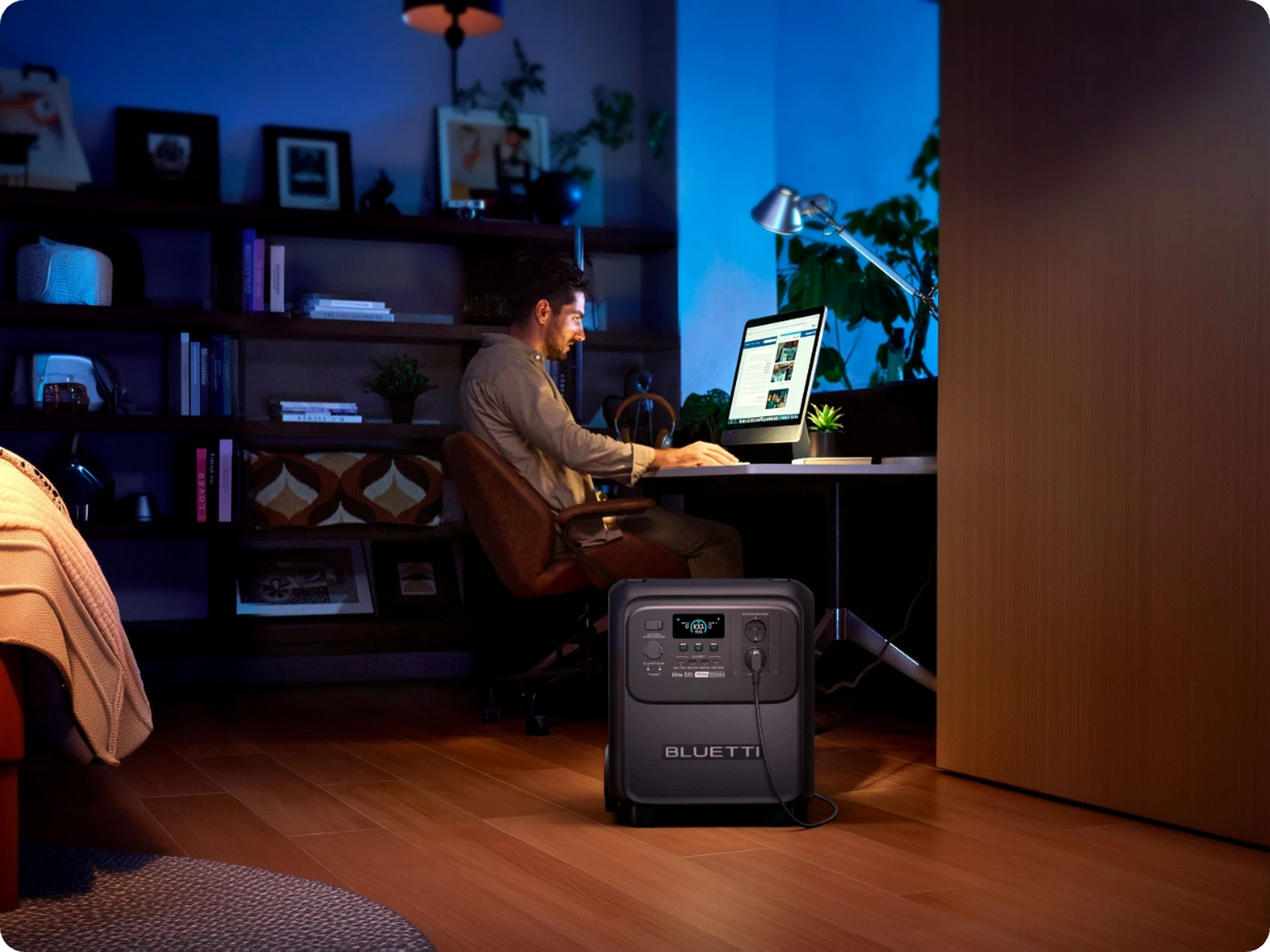 Mężczyzna pracuje przy biurku, generator prądu na pierwszym planie, ciemny pokój.