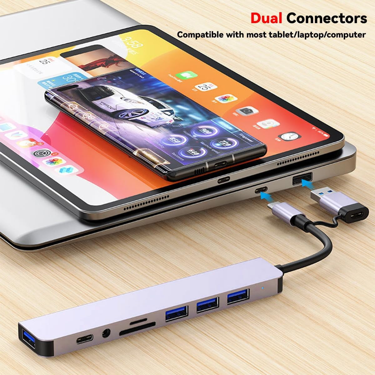 Ein grauer USB-Hub mit mehreren Anschlüssen, verbunden mit einem Laptop, auf dem ein Tablet liegt.