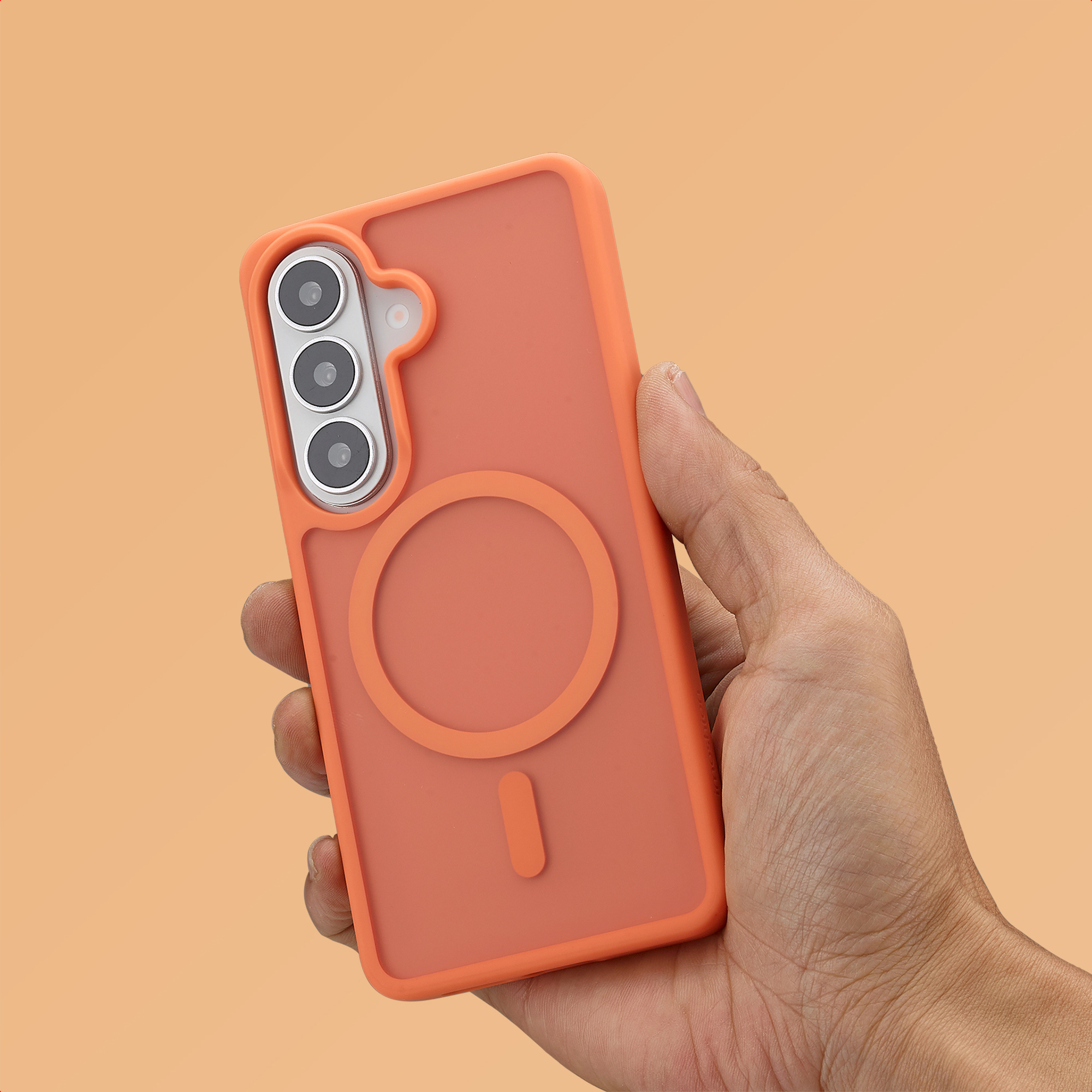 Een hand houdt een oranje telefoonhoesje met drie cameralenzen vast.