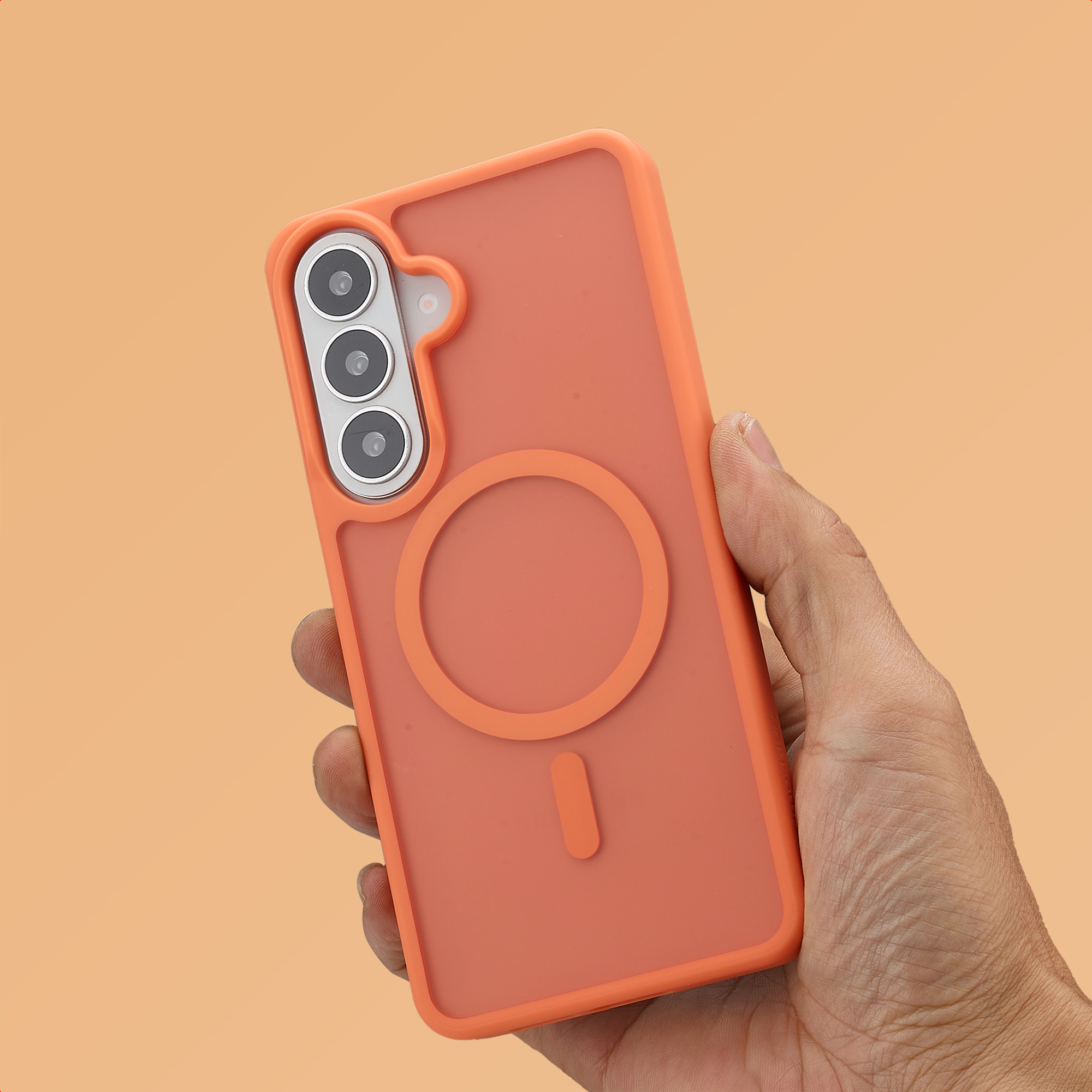 Una mano tiene una cover arancione per telefono con fotocamere e anello magnetico.